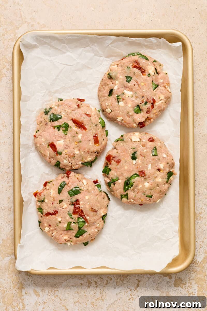 Ground turkey burger patties on parchment lined baking sheet.