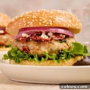 Turkey burger with spinach and feta on bun with lettuce, onion and other ingredients.