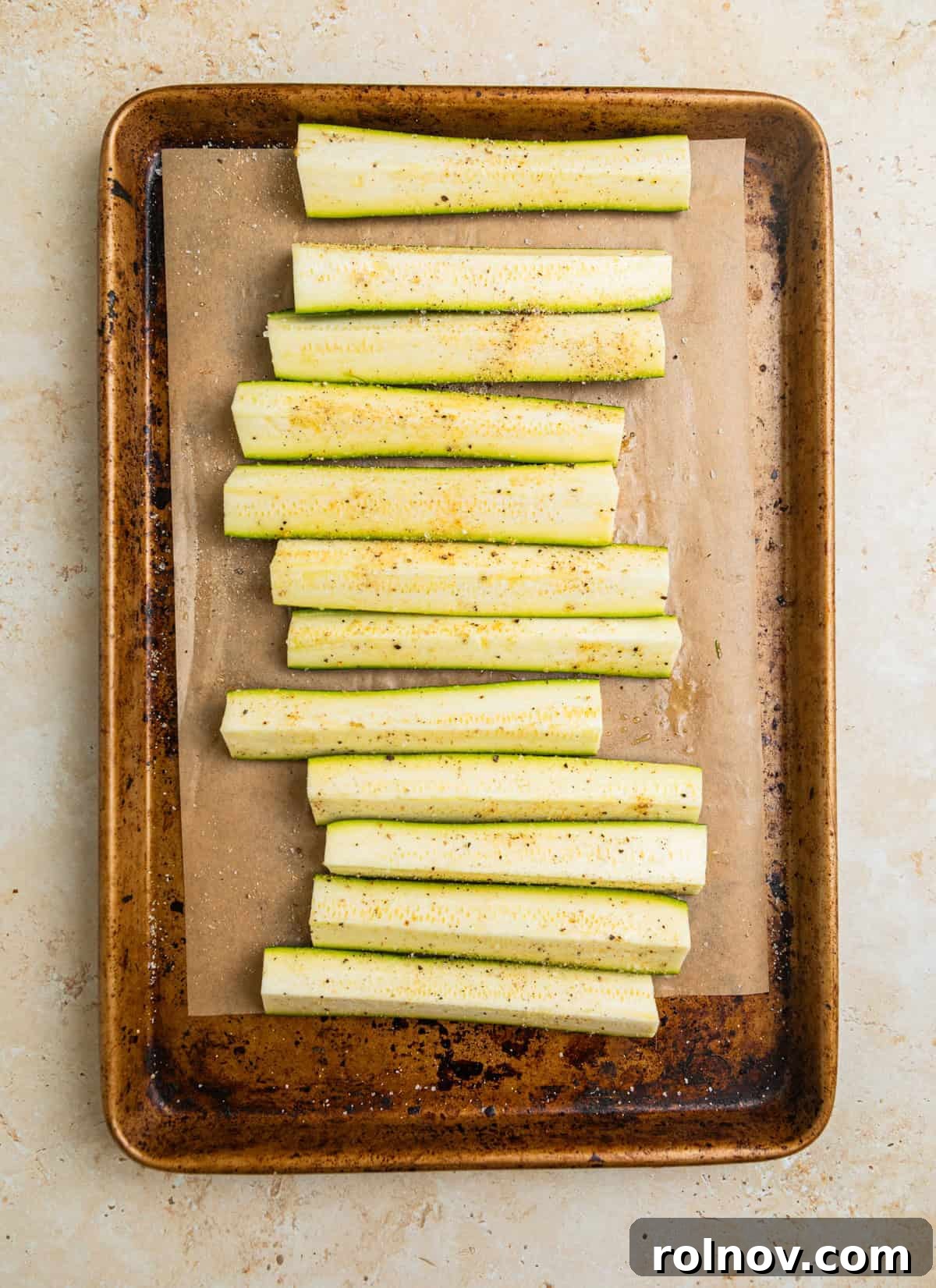 Charred Zucchini Pasta Toss 4 Sliced zucchini pieces coated with olive oil and spices, arranged on a parchment-lined baking sheet, ready for grilling.