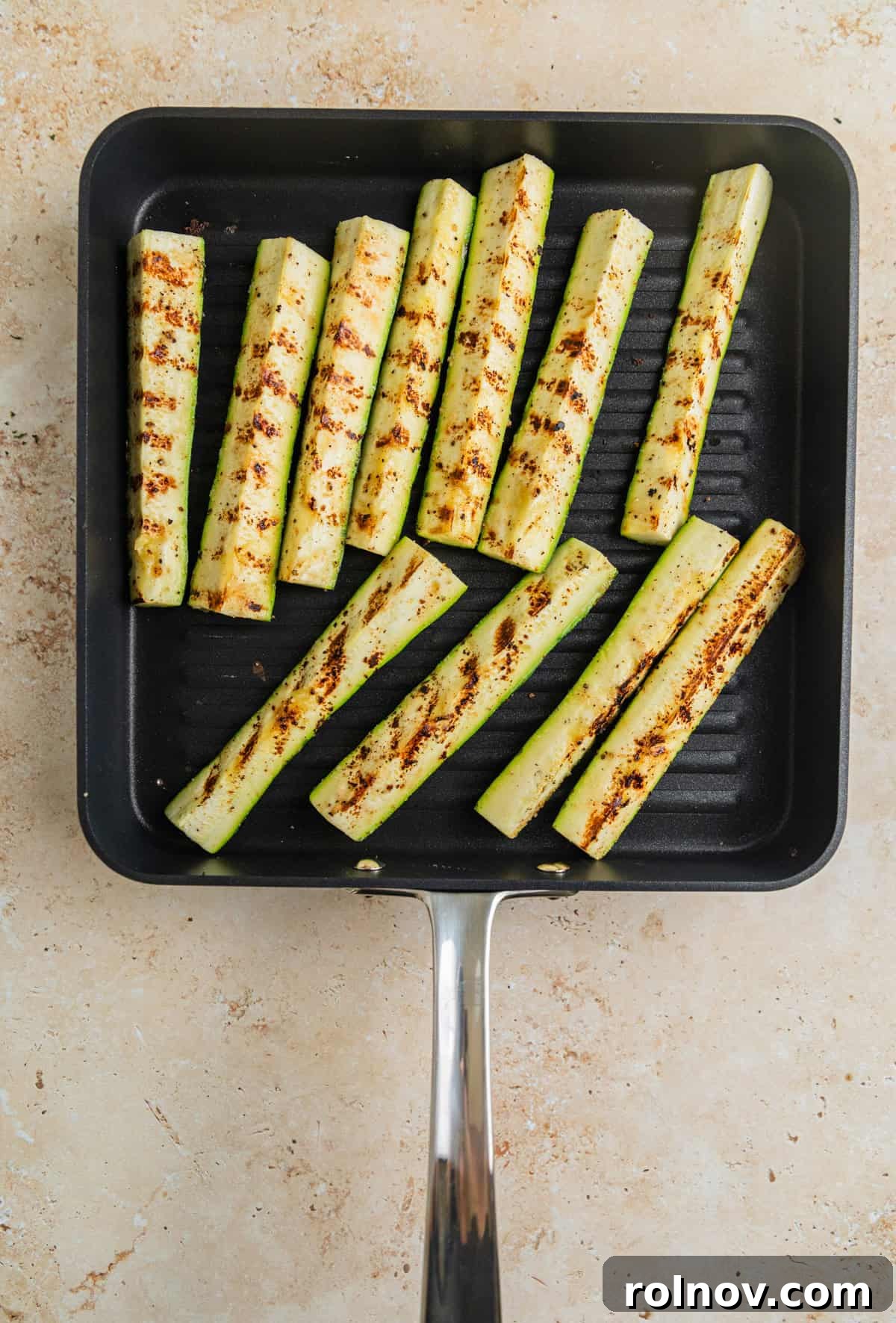 Charred Zucchini Pasta Toss 5 Zucchini spears grilling on a grill pan, showing visible char marks and steam, cooking to tender perfection.