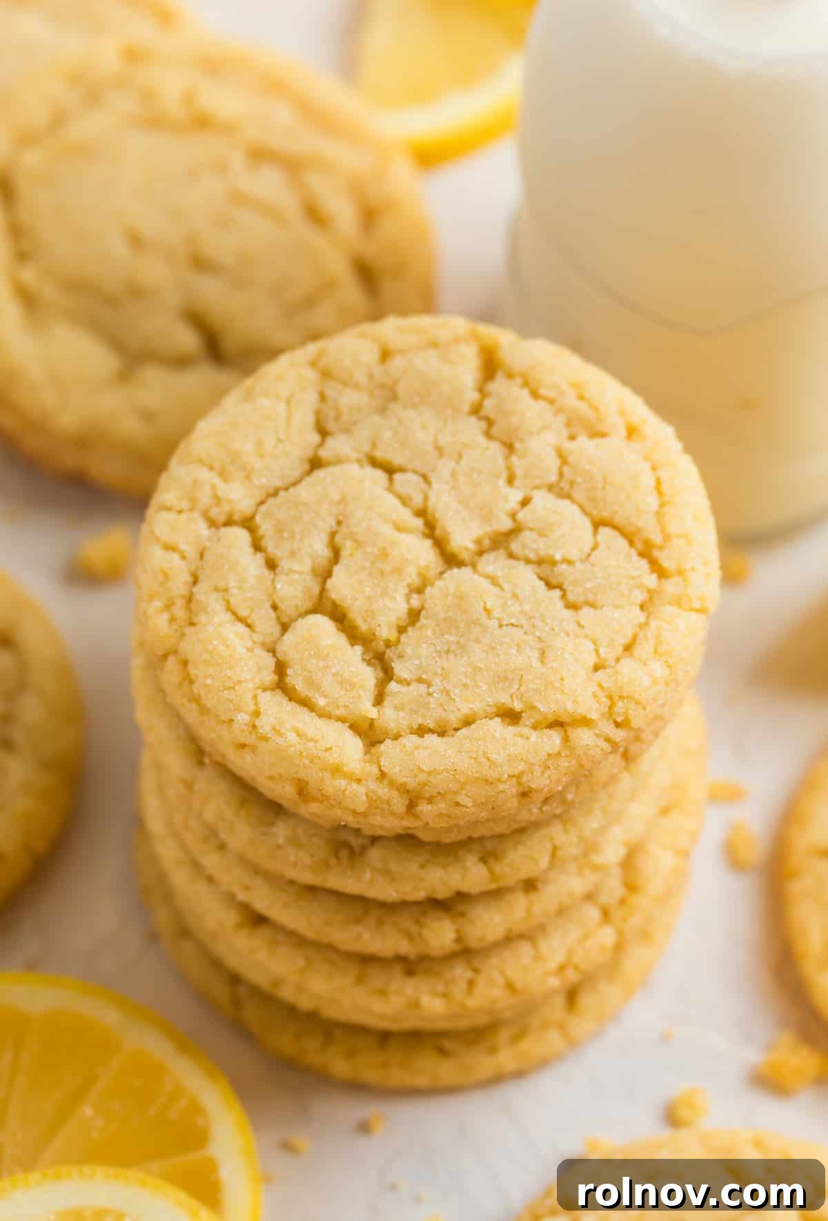 Bright Lemon Sugar Cookies 2 Stack of lemon sugar cookies with glass of milk and lemon wedges surrounding.