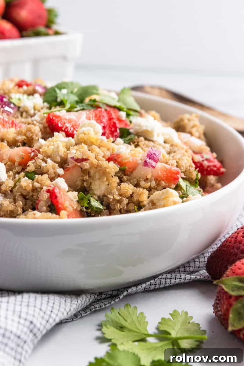 Refreshing Summer Strawberry Quinoa 6 Strawberry quinoa salad in white serving bowl with a white napkin and silver serving spoon.