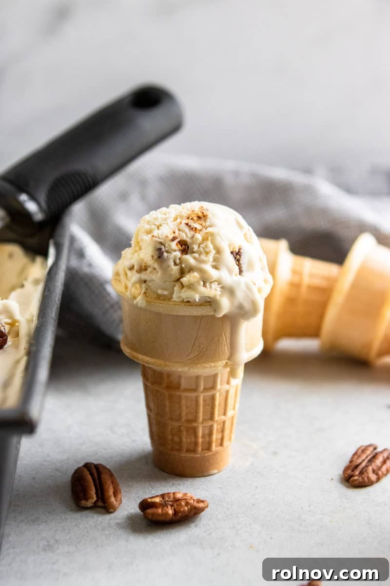 A perfectly scooped butter pecan ice cream cone, with extra cones in the background.