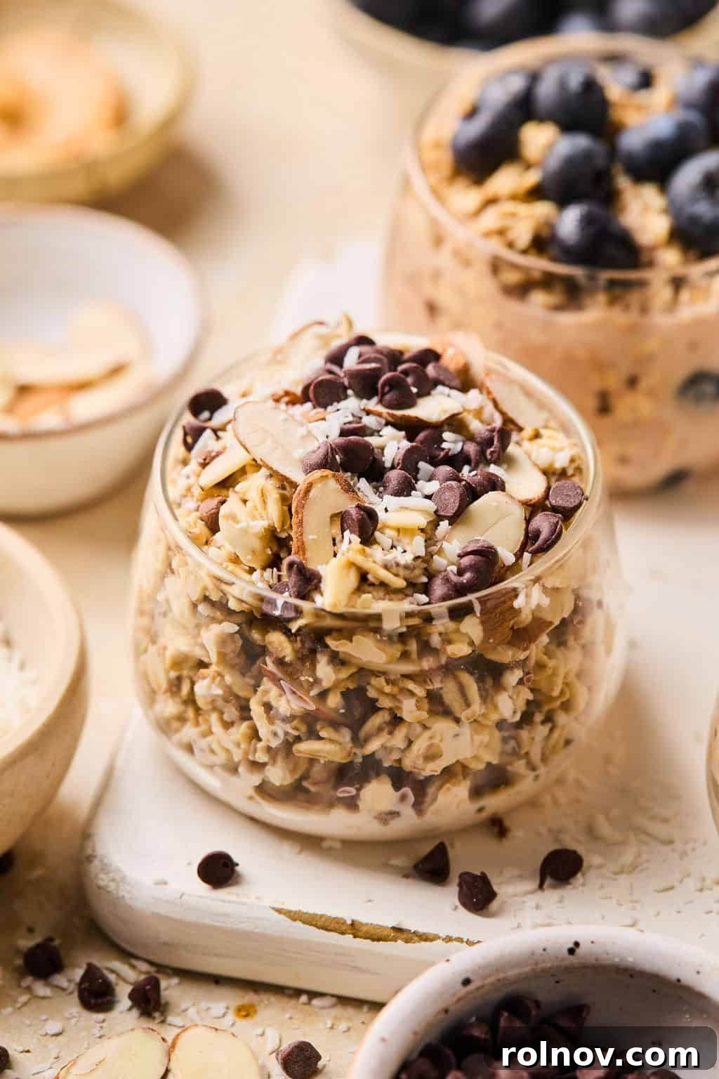 6 Simple Overnight Oats to Master Your Mornings 11 Almond, coconut and chocolate chip oats in glass with other dishes surrounding.
