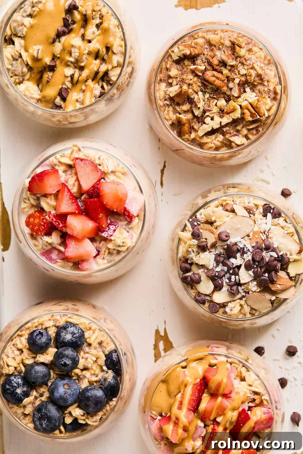 6 Simple Overnight Oats to Master Your Mornings 13 Overhead view of six easy overnight oats recipes prepared in glass dishes including peanut butter and jelly, blueberry muffin, peanut butter chocolate and more.