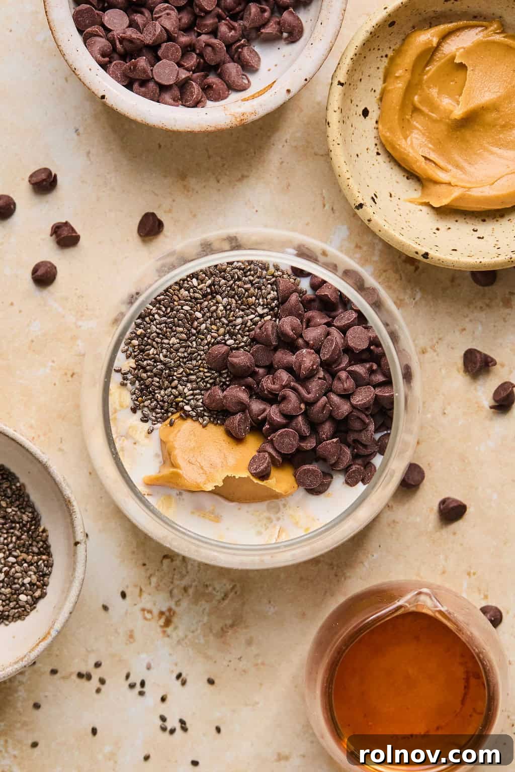 6 Simple Overnight Oats to Master Your Mornings 5 Ingredients for peanut butter chocolate oatmeal arranged on surface with them all added to jar before stirring.