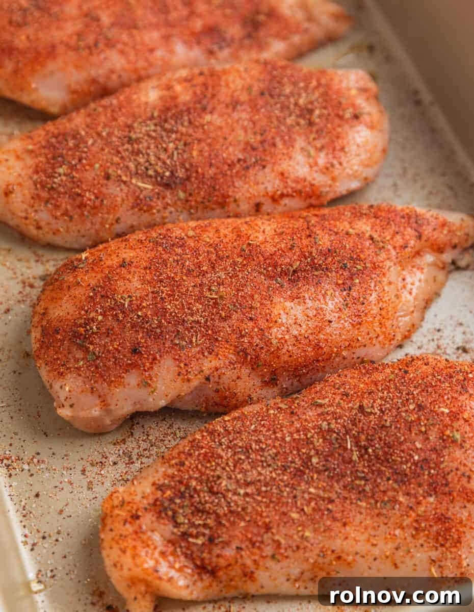 Tropical Mango Chicken 4 Seasoned raw chicken breasts arranged in a baking pan, ready for the oven.