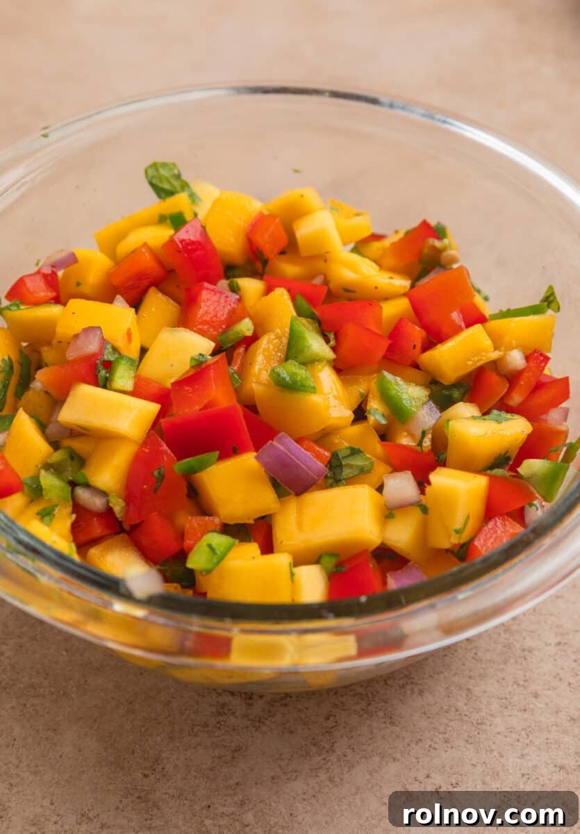 Tropical Mango Chicken 7 A vibrant and freshly mixed mango salsa in a clear glass bowl, showcasing its colorful ingredients.