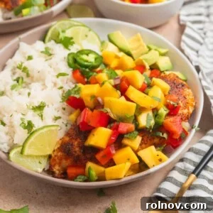 Mango salsa chicken served on plate with white rice and lime.