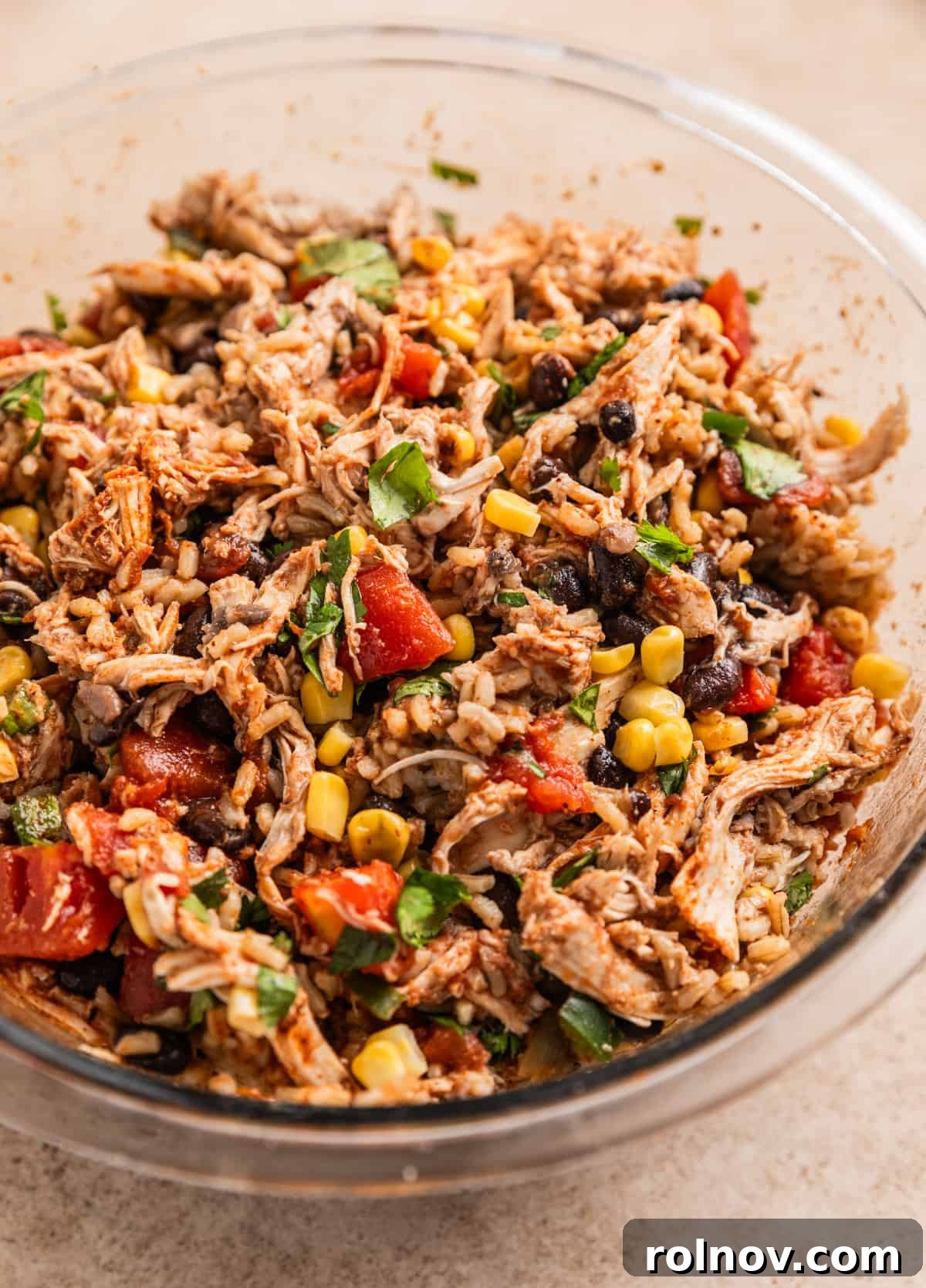 Savory Chicken Poblano Boats 4 A glass mixing bowl filled with the colorful chicken, rice, tomato, corn, and black bean mixture, ready for stuffing.