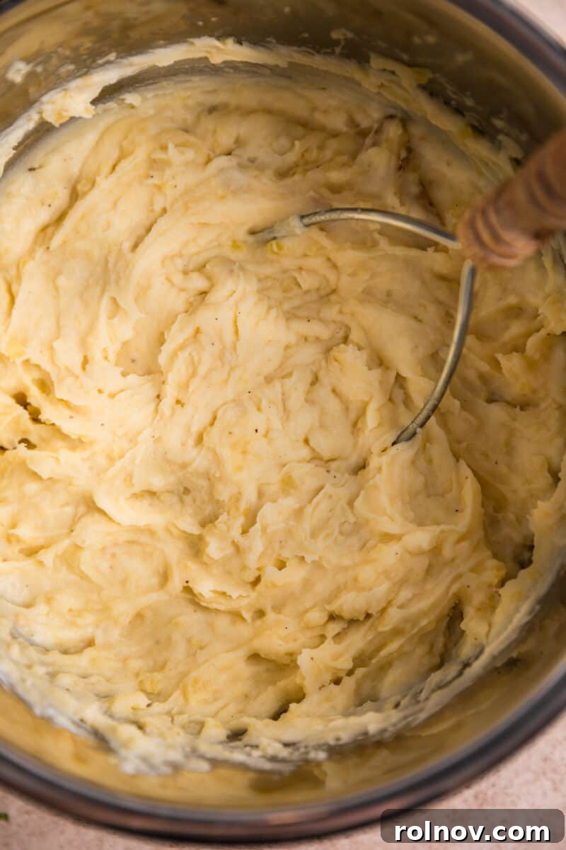 Creamy Instant Pot Garlic Parmesan Mashed Potatoes 6 Potato masher in Instant Pot after mashing.