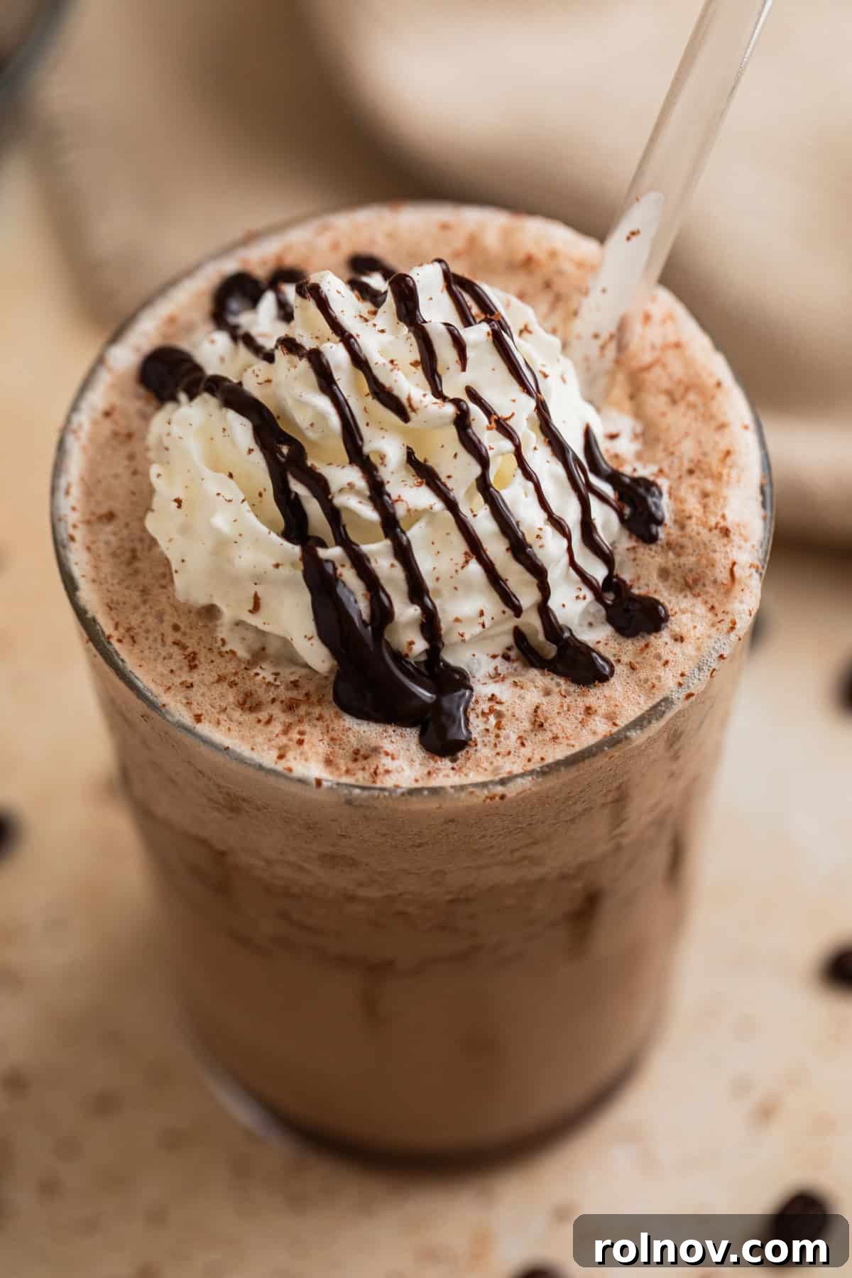 Decadent Homemade Mocha Frappuccino 2 Mocha frappuccino in a glass with whipped cream and chocolate drizzle on top, showcasing a delightful homemade treat.