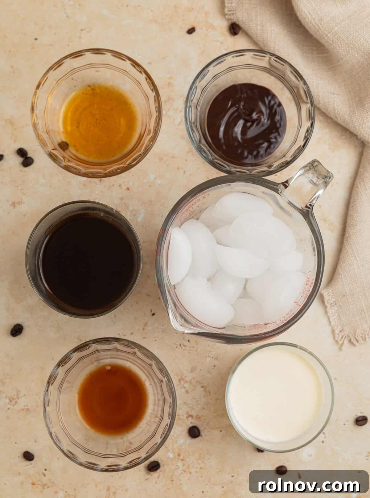 Decadent Homemade Mocha Frappuccino 3 Ice, vanilla, coffee, and other ingredients laid out on a clean surface, ready for blending.