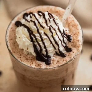 Decadent Homemade Mocha Frappuccino 7 Mocha frappuccino iced coffee drink in glass with whipped cream and chocolate shavings.