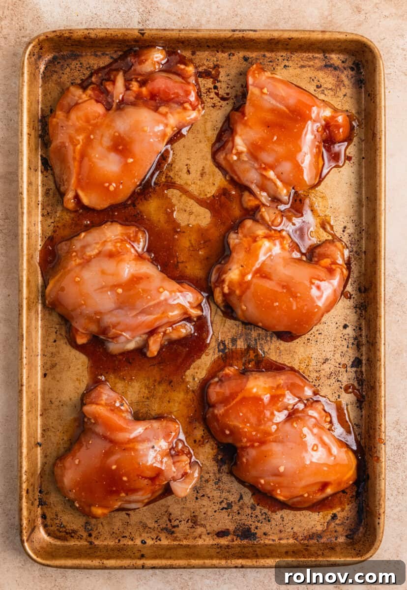 One-Pan Honey Garlic Chicken Thigh Dinner 6 Marinated chicken thighs arranged on sheet pan.