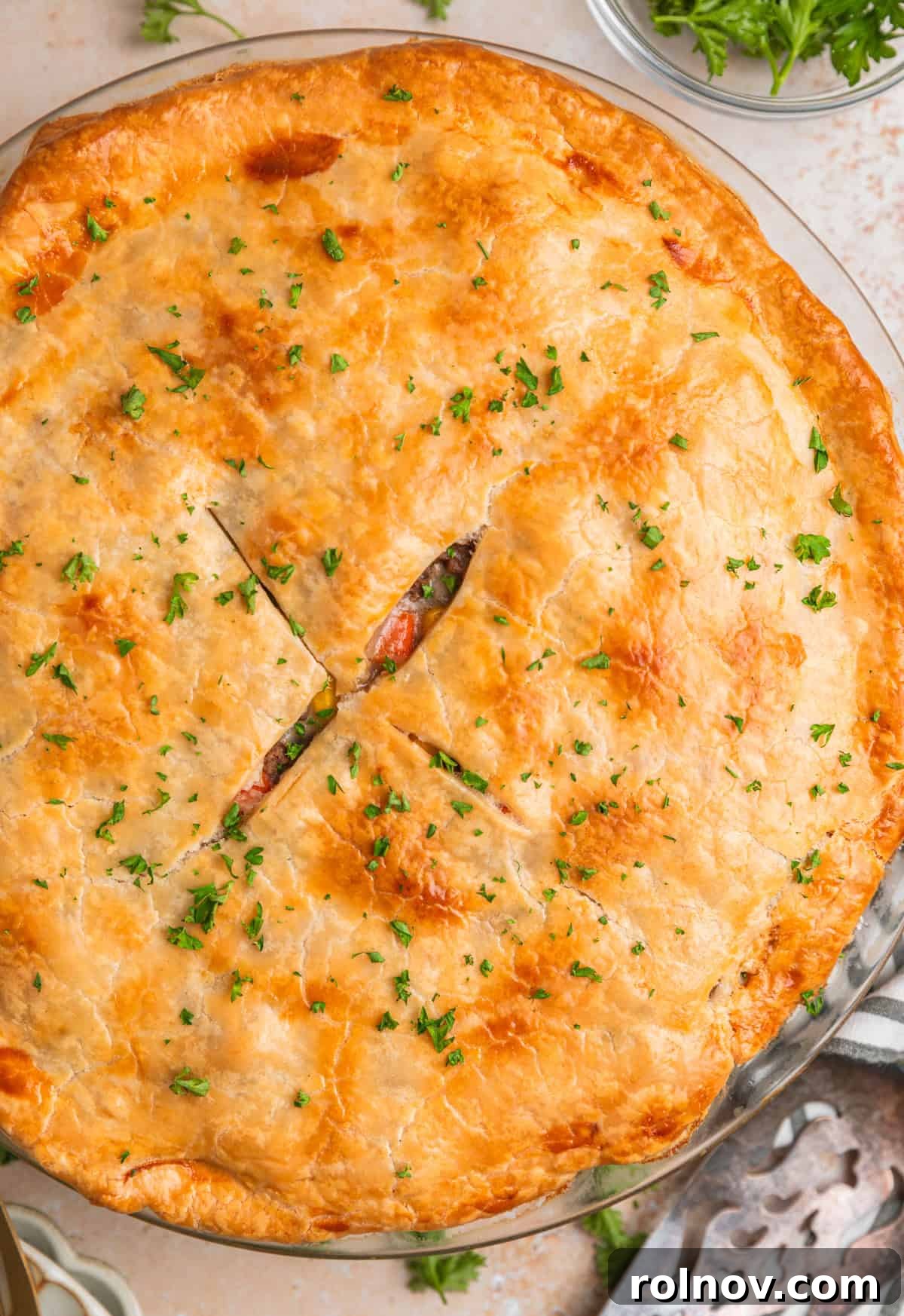 Hearty Beef Pot Pie 12 A close-up view of a perfectly baked ground beef pot pie, beautifully garnished with fresh chopped parsley, highlighting its golden, flaky crust and savory appeal.