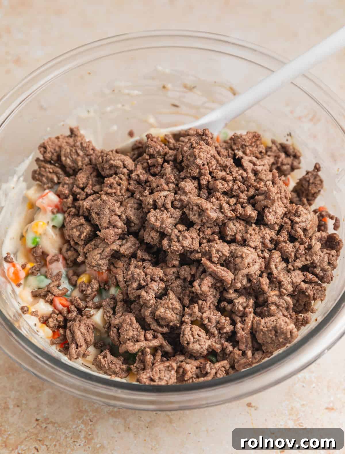 Hearty Beef Pot Pie 6 Browned ground beef being added to the vegetable and soup mixture in a large mixing bowl, ready for final combination.