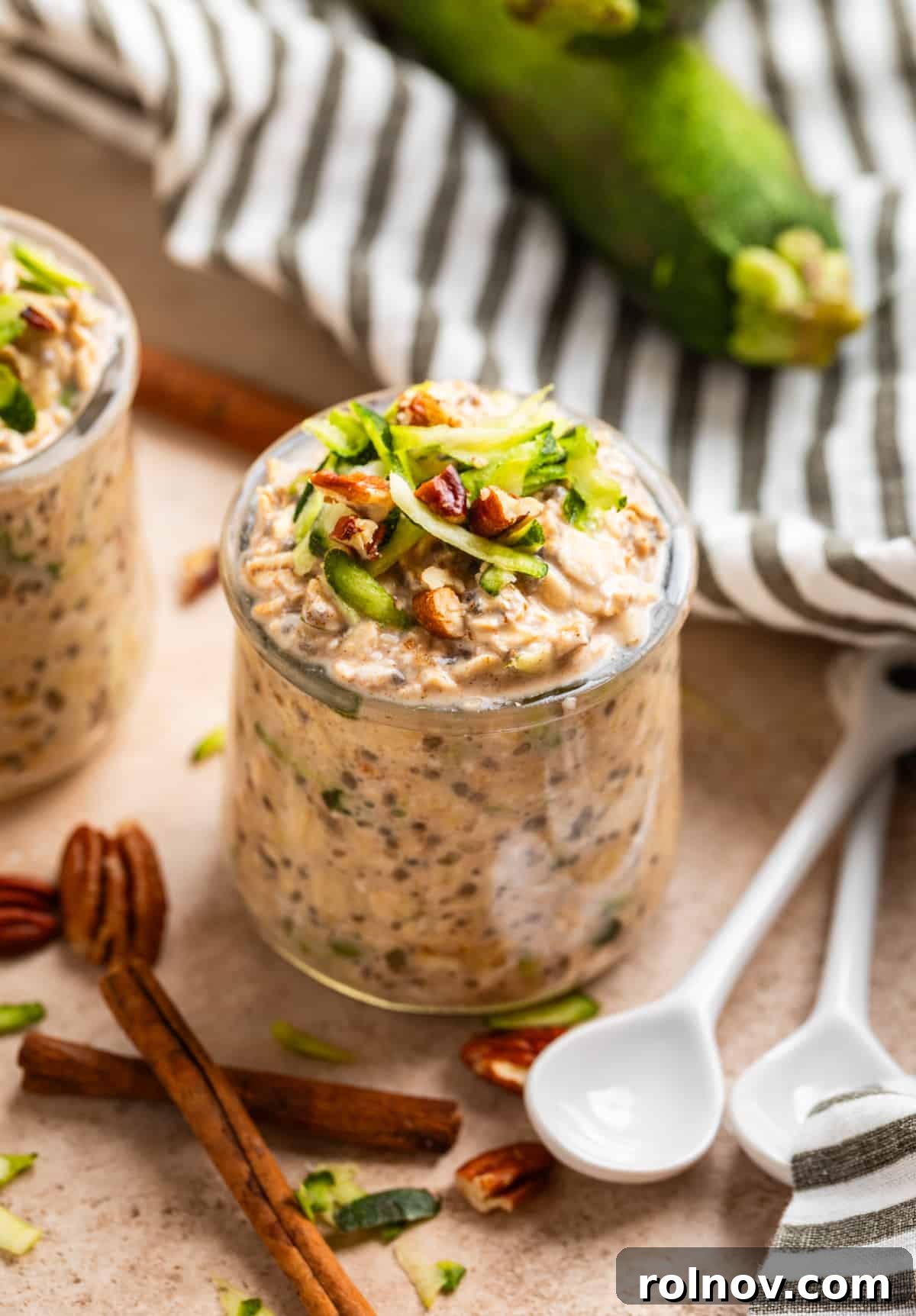 No-Bake Zucchini Bread Breakfast 2 Zucchini overnight oats in jar with shredded zucchini and chopped pecans on top.