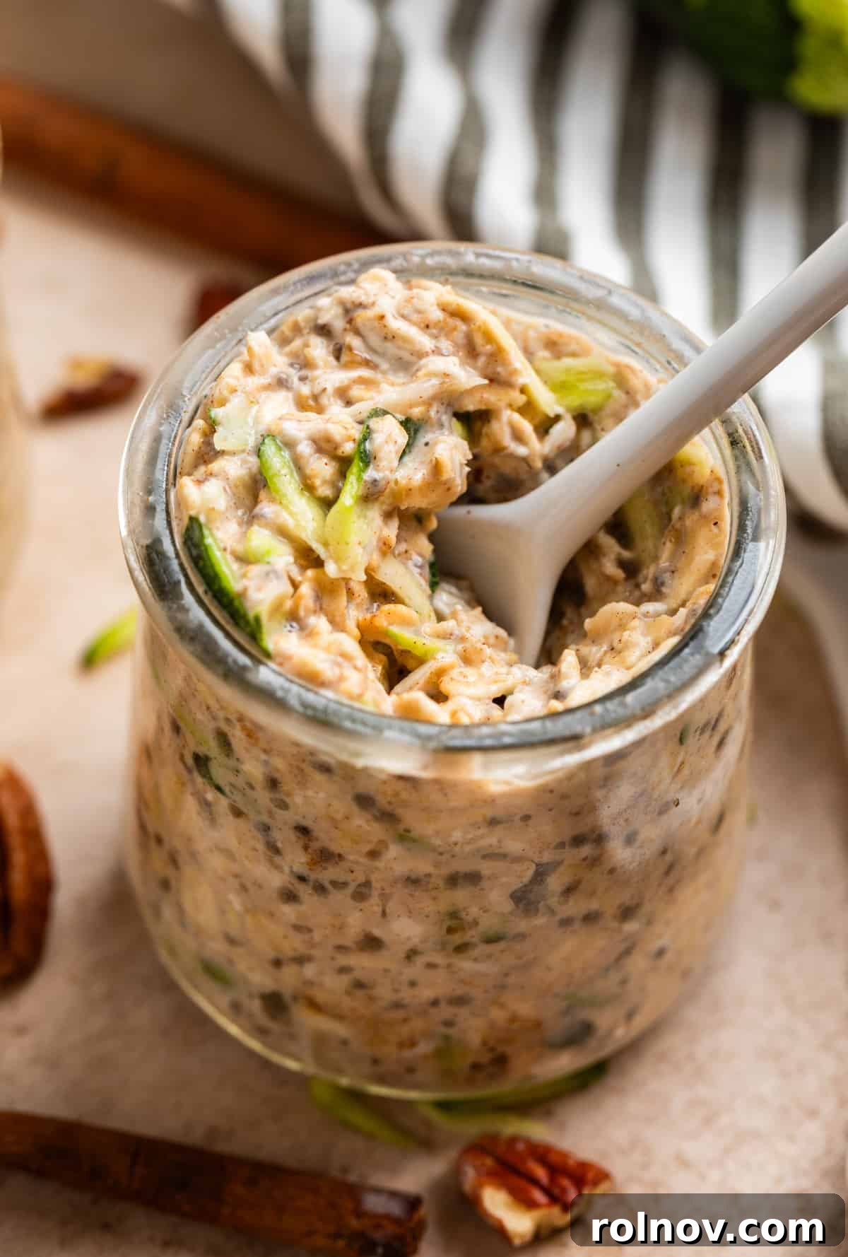 No-Bake Zucchini Bread Breakfast 4 White spoon scooping into a jar of zucchini bread overnight oats.