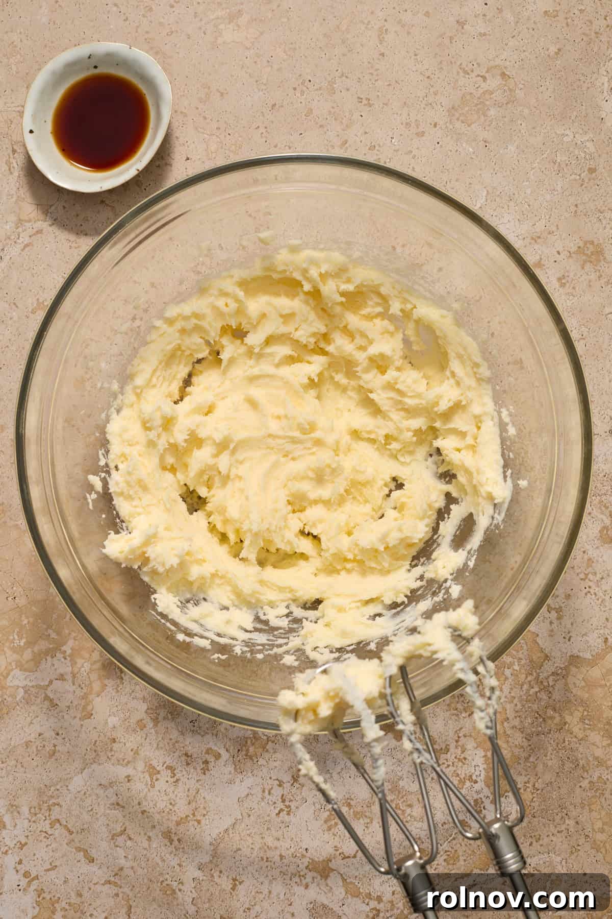 Velvety Pecan Cream Cheese Snowflakes 7 Creamed butter, cream cheese and sugar in glass bowl with vanilla set next to bowl.