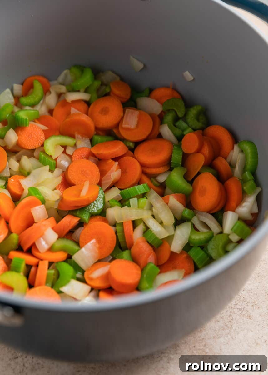 Shortcut Rotisserie Chicken Noodle Soup 5 Sautéed carrots, celery, and onion cooking in a Dutch oven pot, forming the aromatic base of the soup.