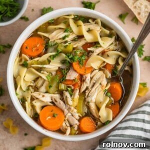 Shortcut Rotisserie Chicken Noodle Soup 10 Overhead view of rotisserie chicken noodle soup in white bowl with spoon.