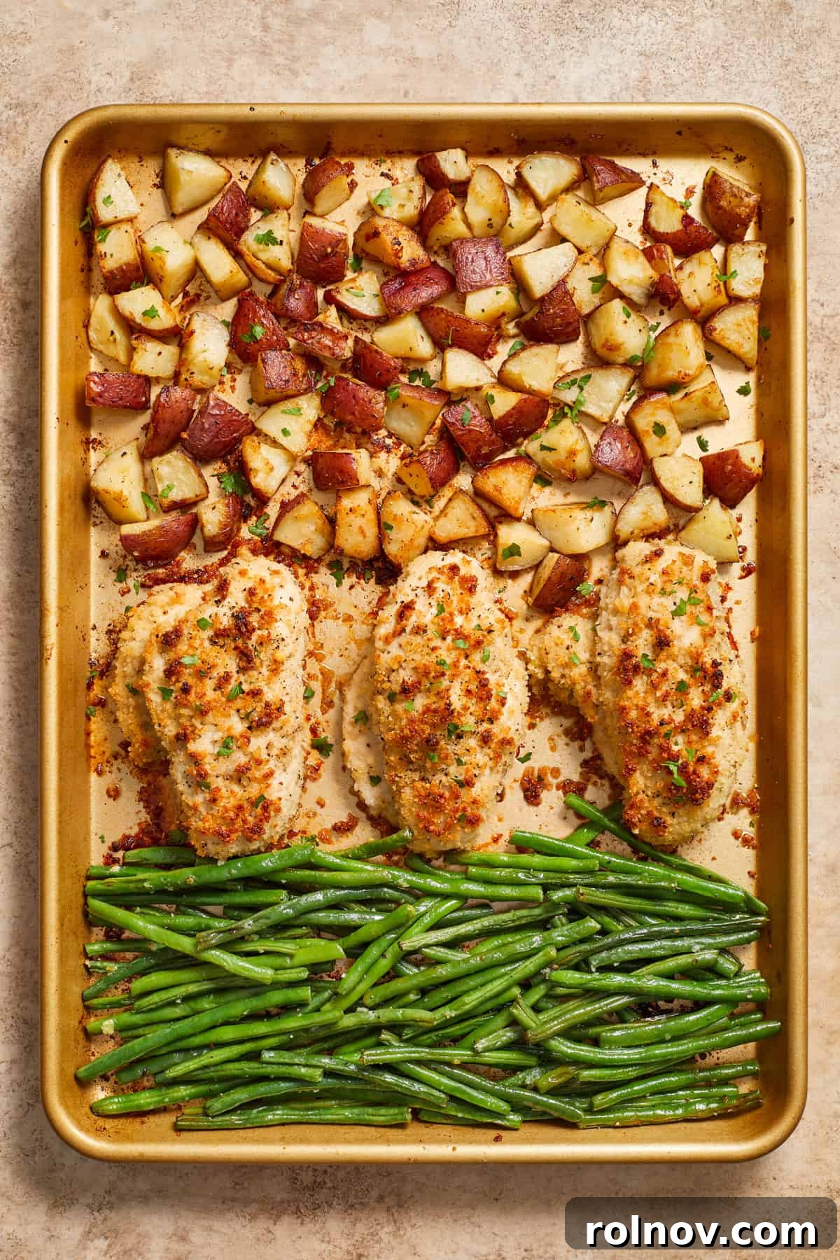 Golden Parmesan Chicken Sheet Pan Feast 2 Parmesan sheet pan chicken dinner cooked with potatoes and green beans on gold pan.