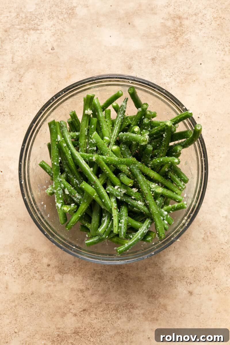 Golden Parmesan Chicken Sheet Pan Feast 9 Green beans in bowl with seasoning and parmesan.