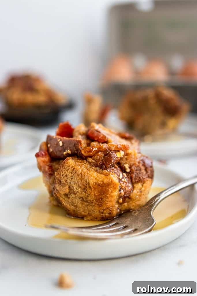 A beautifully plated Maple Bacon French Toast Muffin, glistening with an extra drizzle of maple syrup, accompanied by a fork, ready to be enjoyed.
