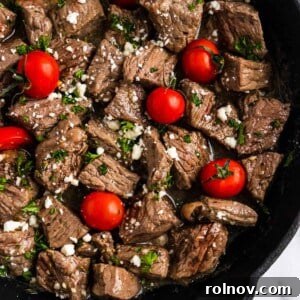 Steak bites in cast iron skillet with tomatoes and feta.