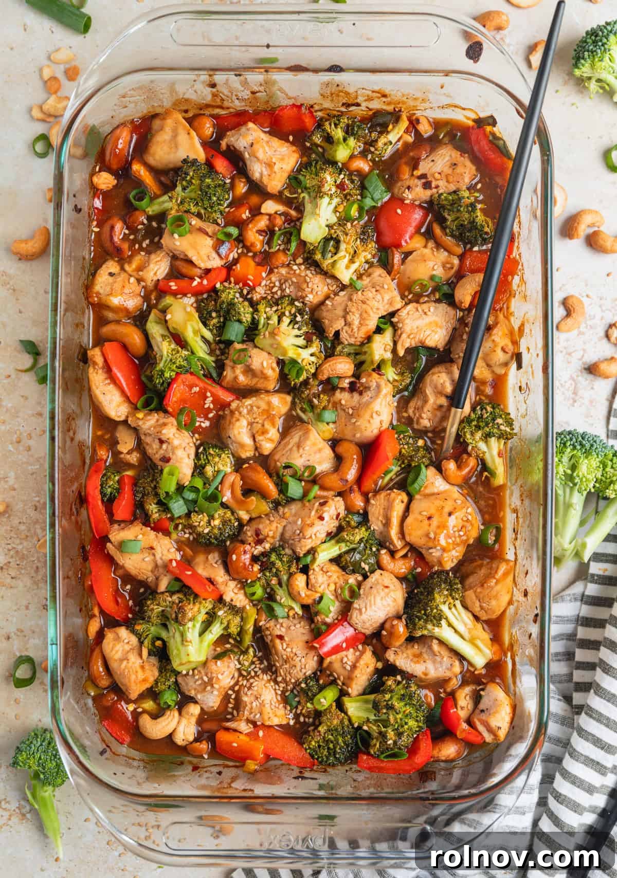 Golden Baked Cashew Chicken 3 Baking pan with easy cashew chicken recipe in sauce and topped with sesame seeds and sliced scallions.