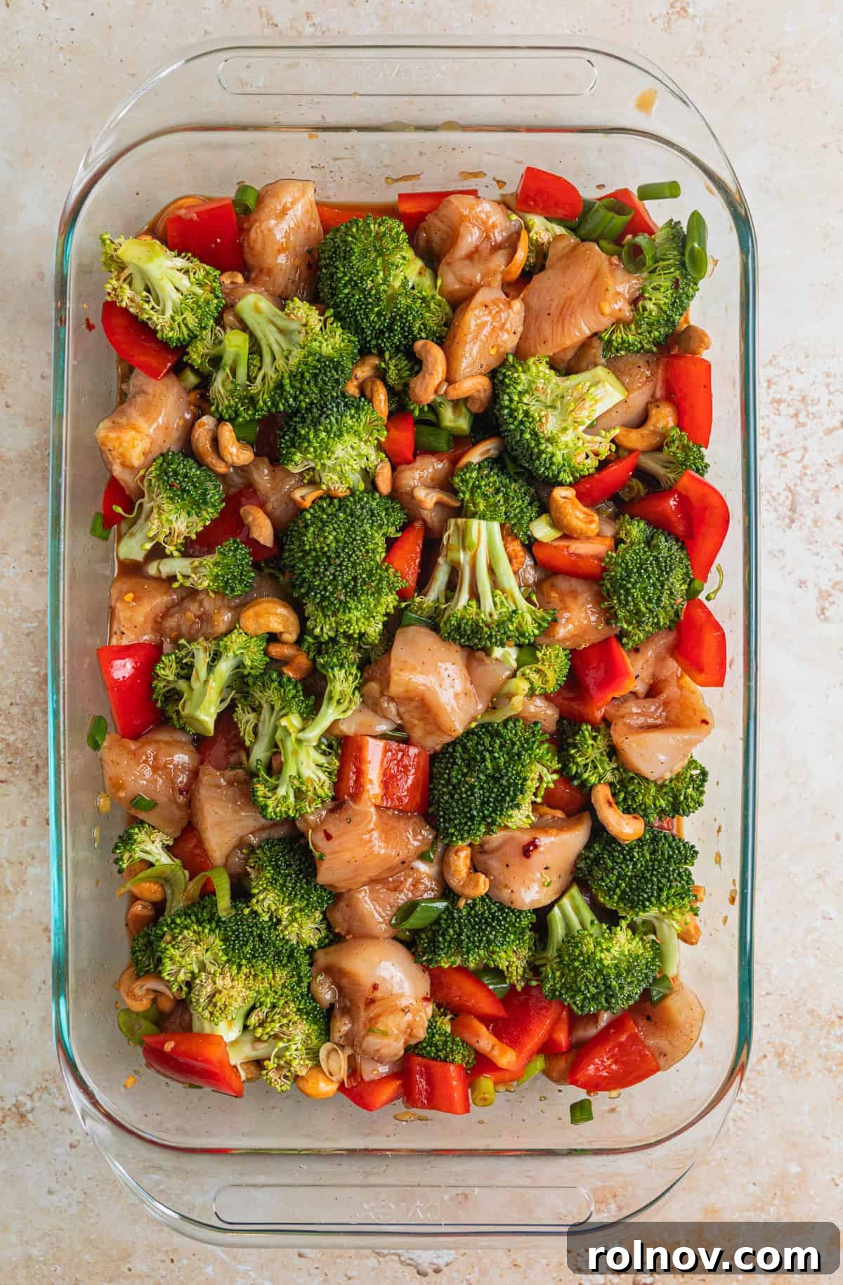 Golden Baked Cashew Chicken 7 Cashew chicken ingredients in glass pan tossed together in sauce before baking.