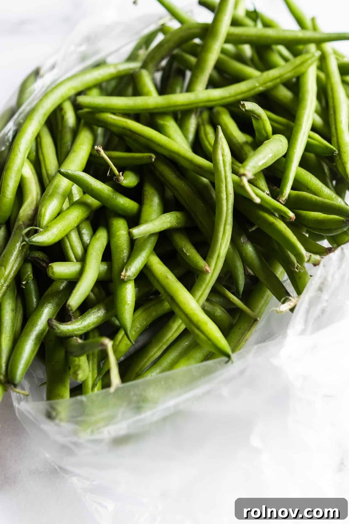 Crispy Roasted Parmesan Green Beans 5 A clear plastic bag filled with fresh, vibrant green beans, ready for preparation.