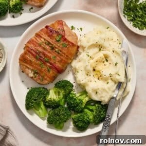 White plate with pork chop dinner including mashed potatoes and broccoli.