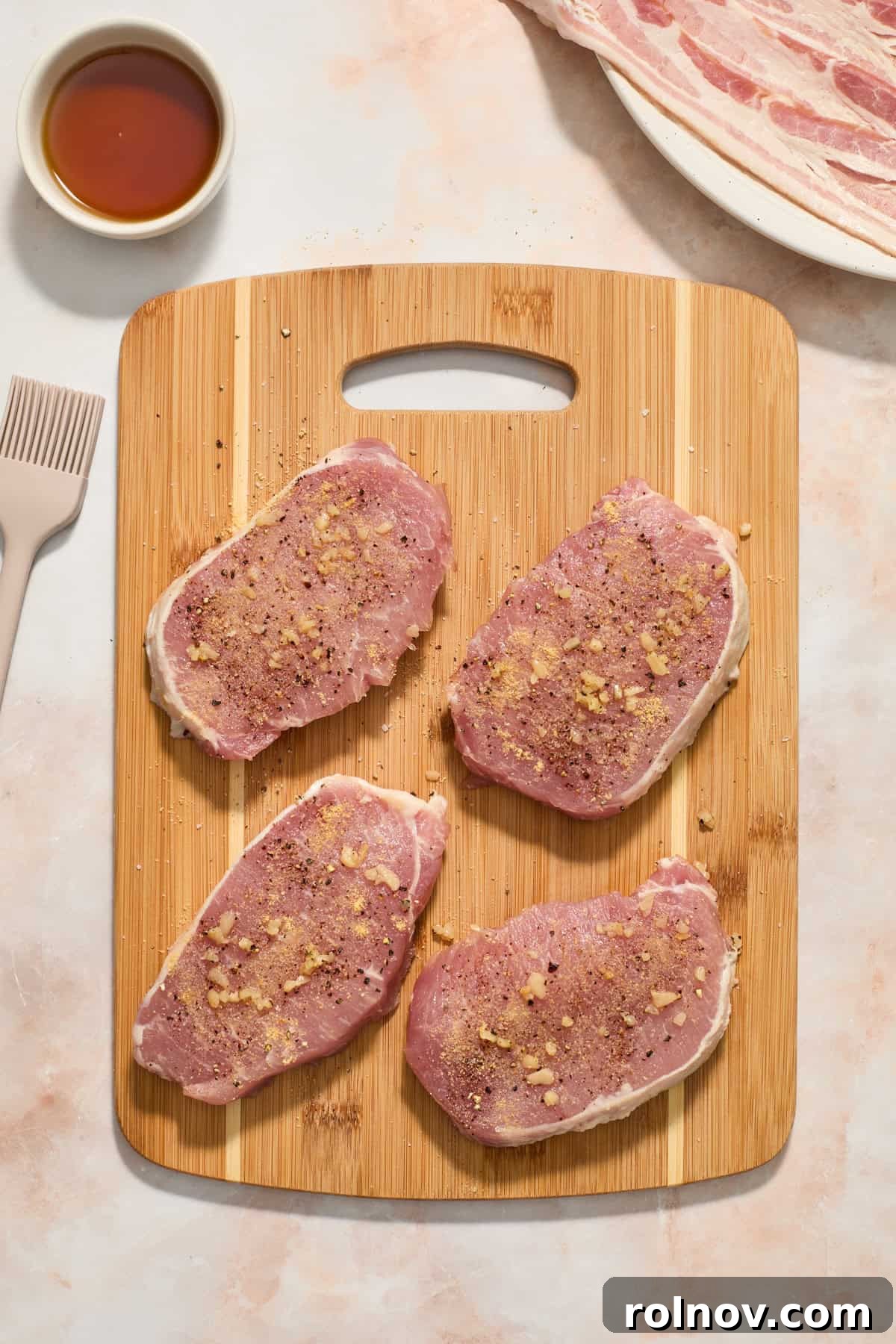 Sweet and Savory Maple Bacon Pork Chops 5 Seasoned pork chops on a wooden cutting board, ready to be wrapped.