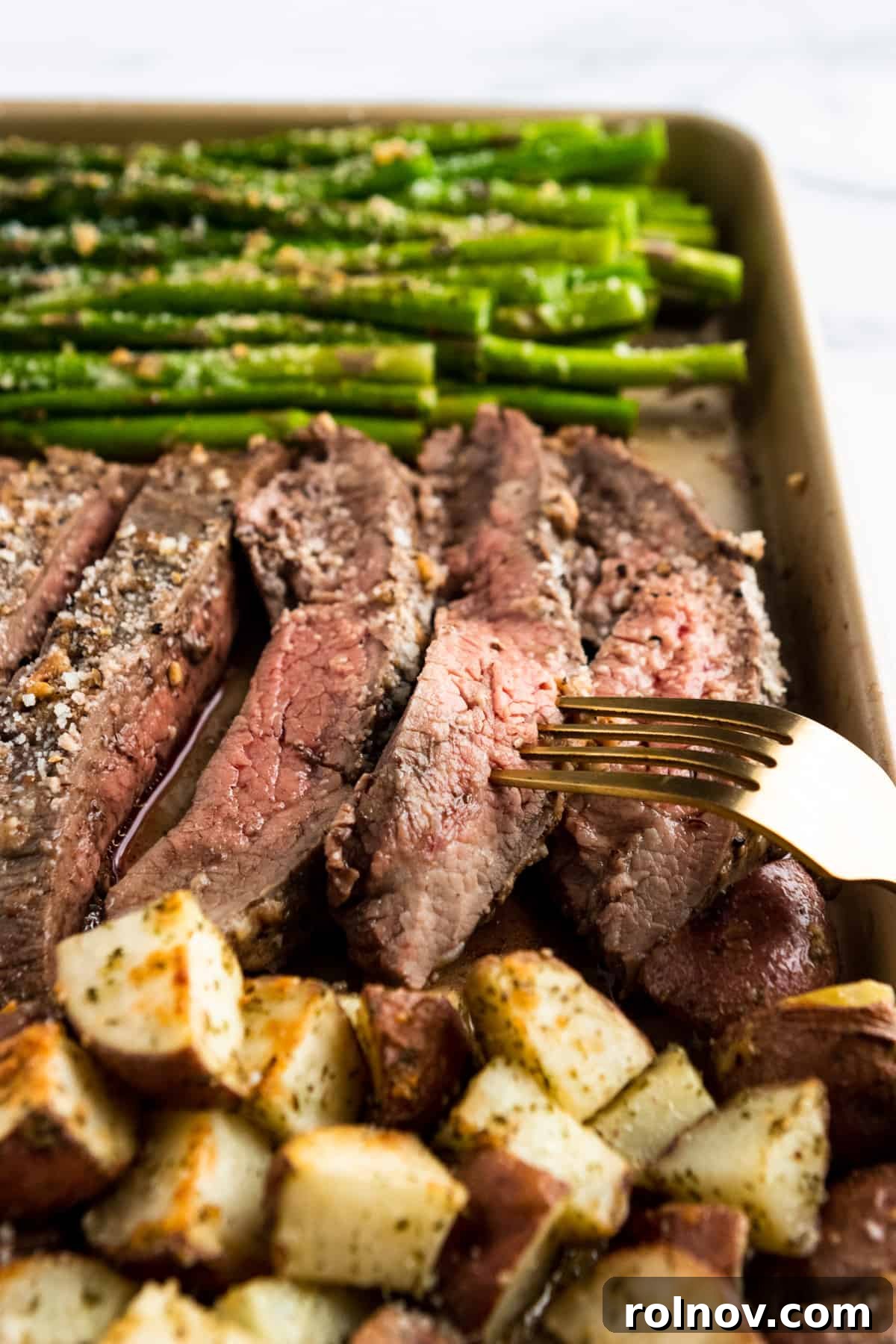 Parmesan Steak and Roasted Potato One-Pan Dinner 2 Parmesan crusted Flank steak sliced on sheet pan with fork.