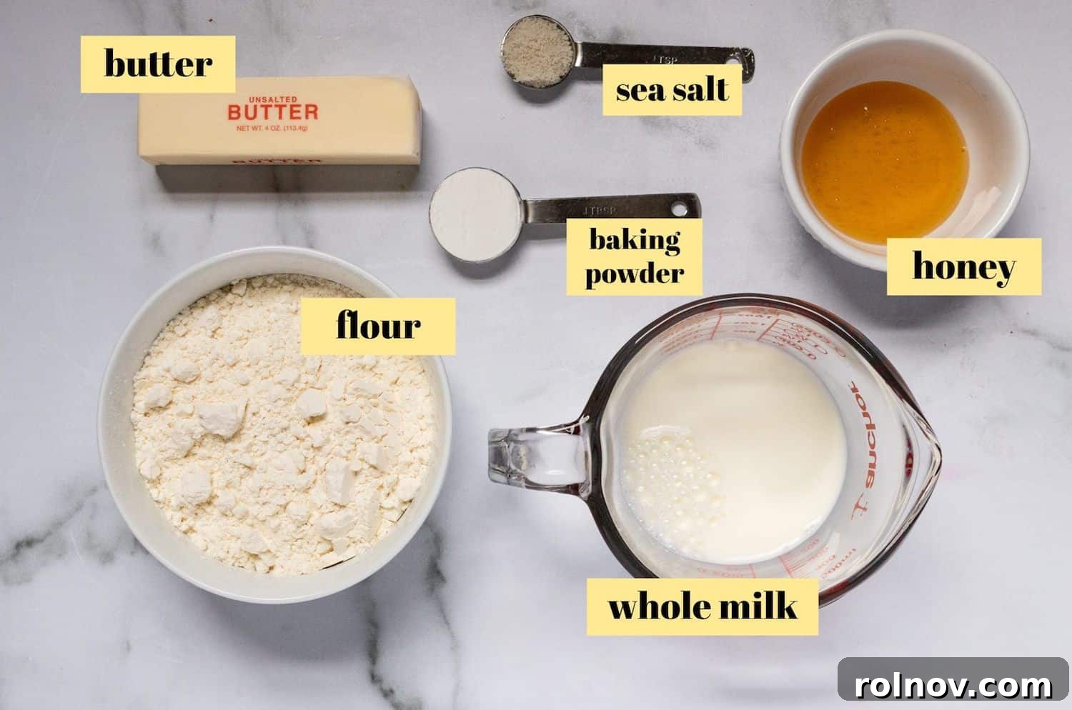 Golden Honey Biscuits 3 A selection of ingredients for honey biscuits, including flour, butter, milk, and honey, neatly arranged on a counter.