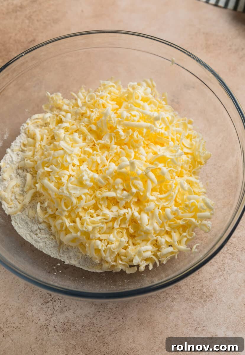 Golden Honey Biscuits 4 Grated butter in glass mixing bowl with flour mixture.