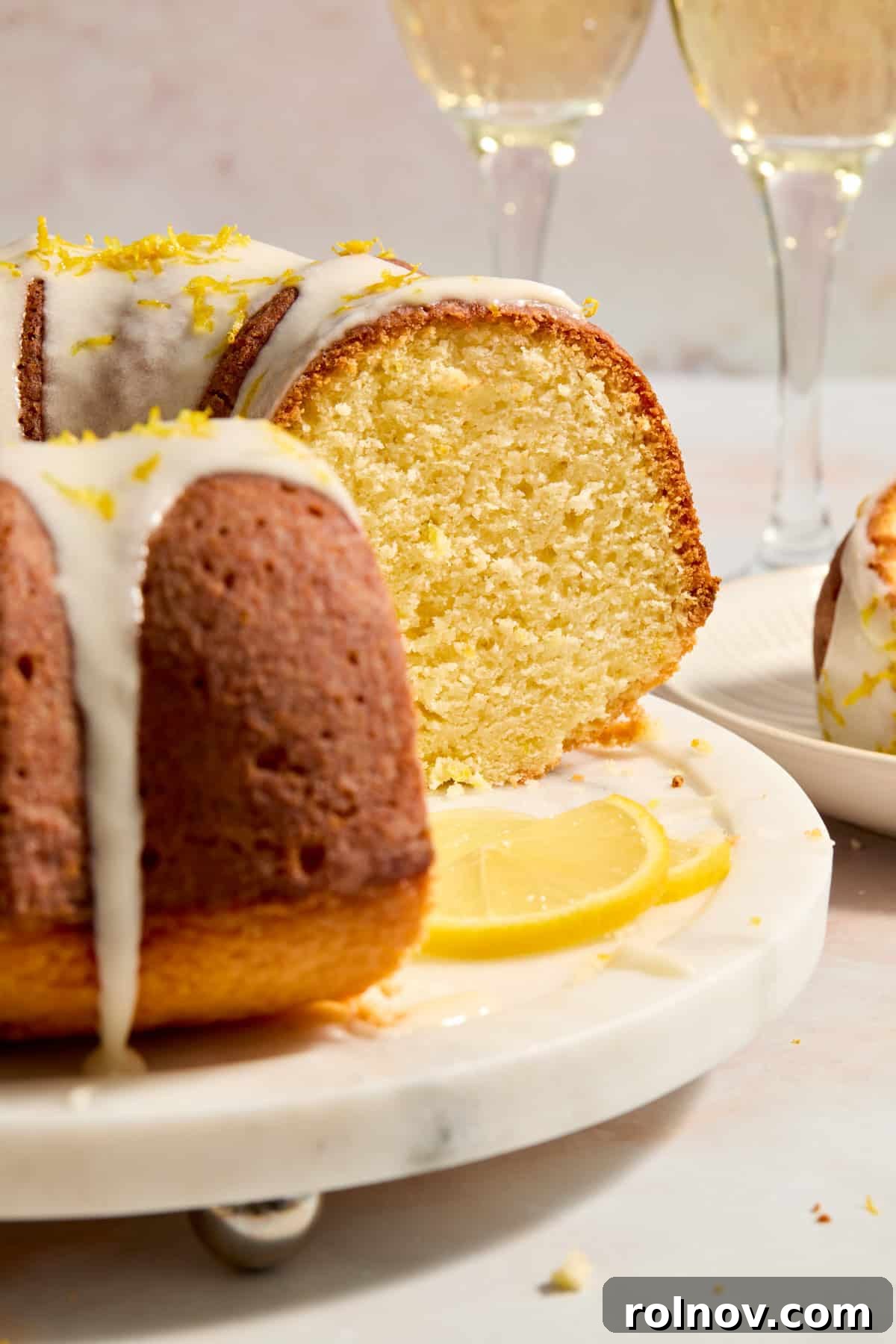 Effervescent Lemon Bundt Cake 3 A freshly baked Champagne Lemon Bundt Cake, generously coated with a shimmering lemon glaze, presented on an elegant cake tray.