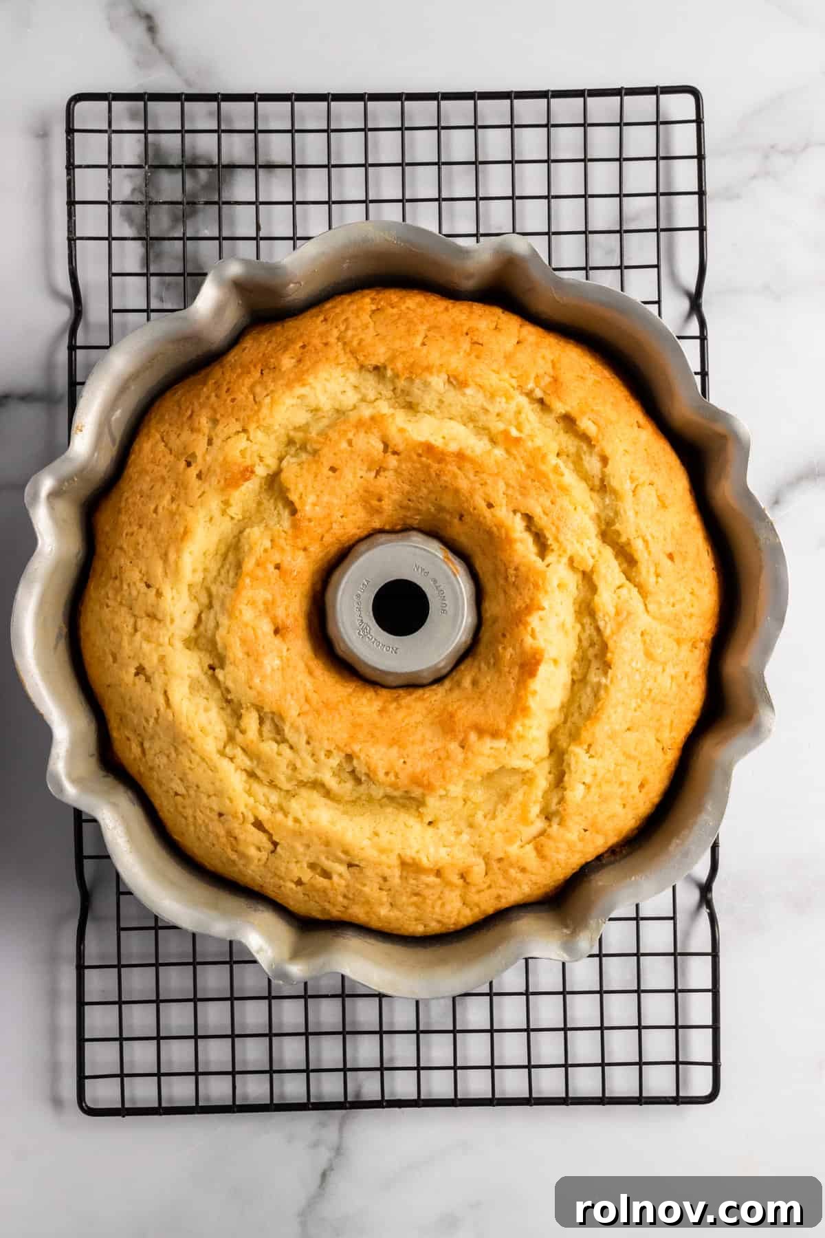 Effervescent Lemon Bundt Cake 9 A freshly baked bundt cake cooling in its pan on a wire rack.