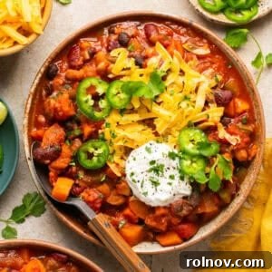 Bowl with vegetarian sweet potato chili with toppings and spoon propped to the side of the bowl.