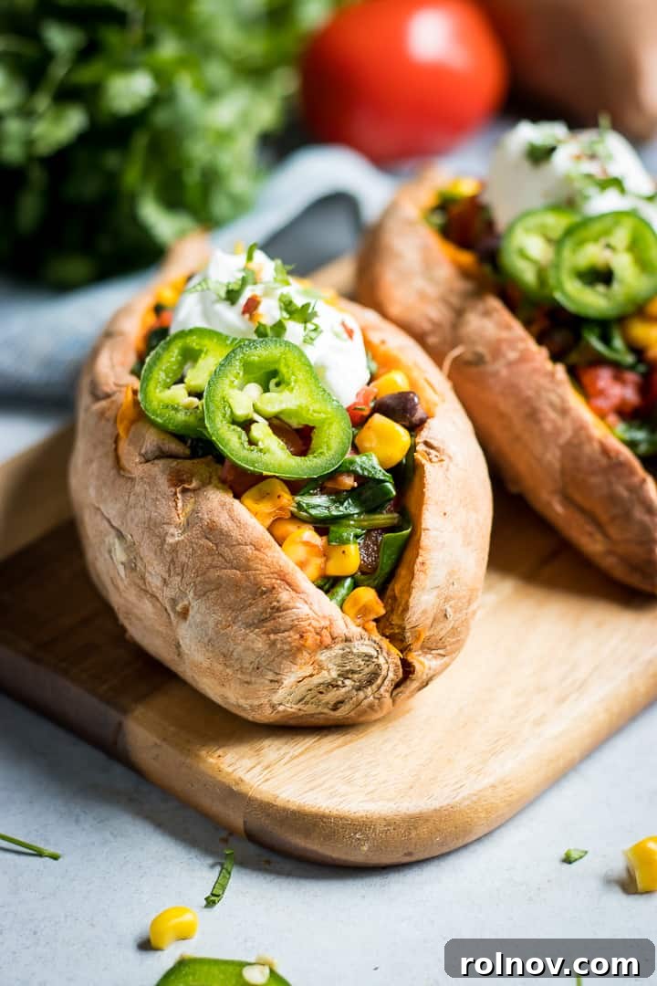 Fiesta Stuffed Sweet Potatoes 2 Sweet potatoes stuffed with veggies and spices on wood cutting board.