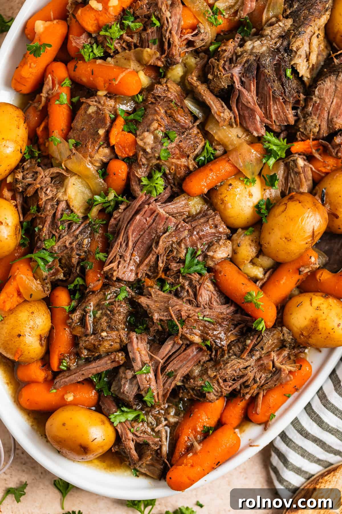 Slow Cooker Beef Pot Roast 3 Overhead view of white platter with shredded chuck roast, carrots, potatoes and onion.