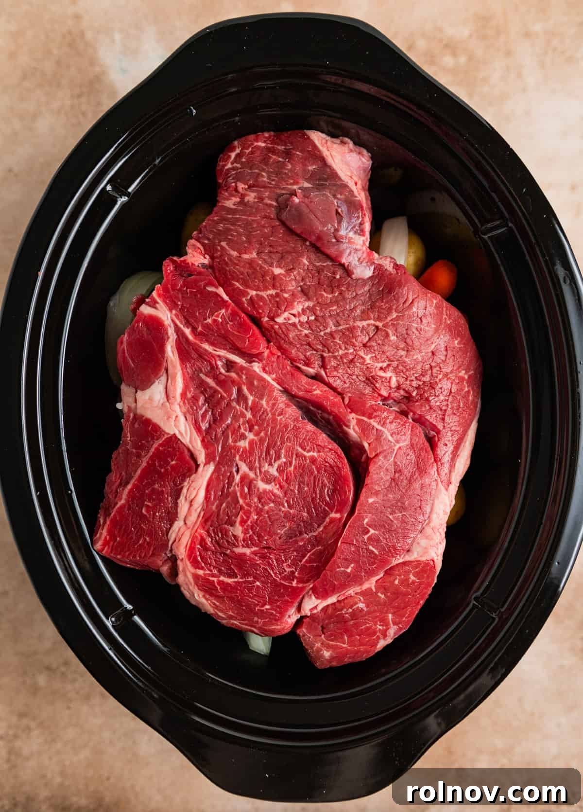 Slow Cooker Beef Pot Roast 6 Chuck roast on top of vegetables in crock pot before cooking.