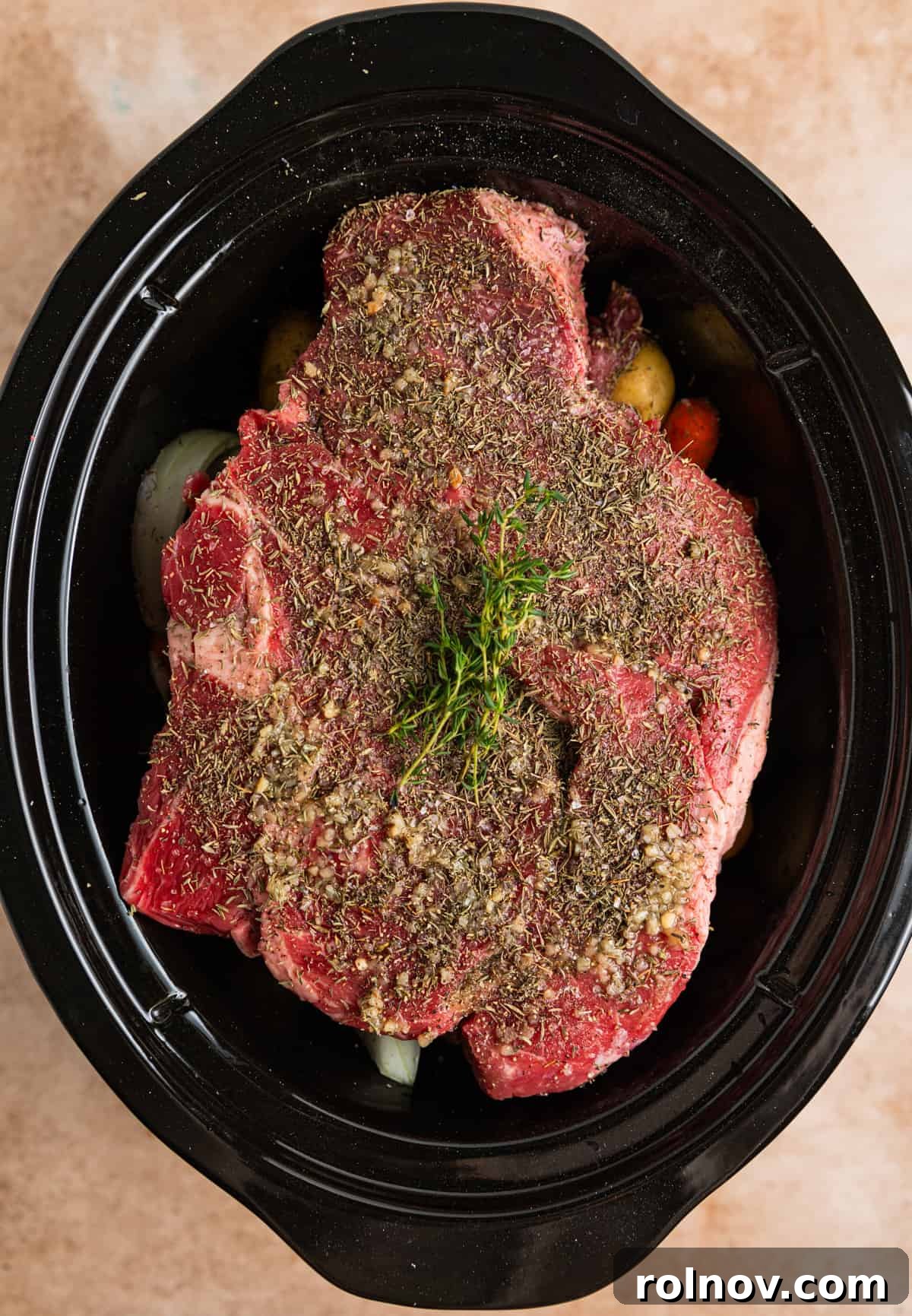 Slow Cooker Beef Pot Roast 7 Seasoning and fresh thyme covering chuck roast in crock pot.