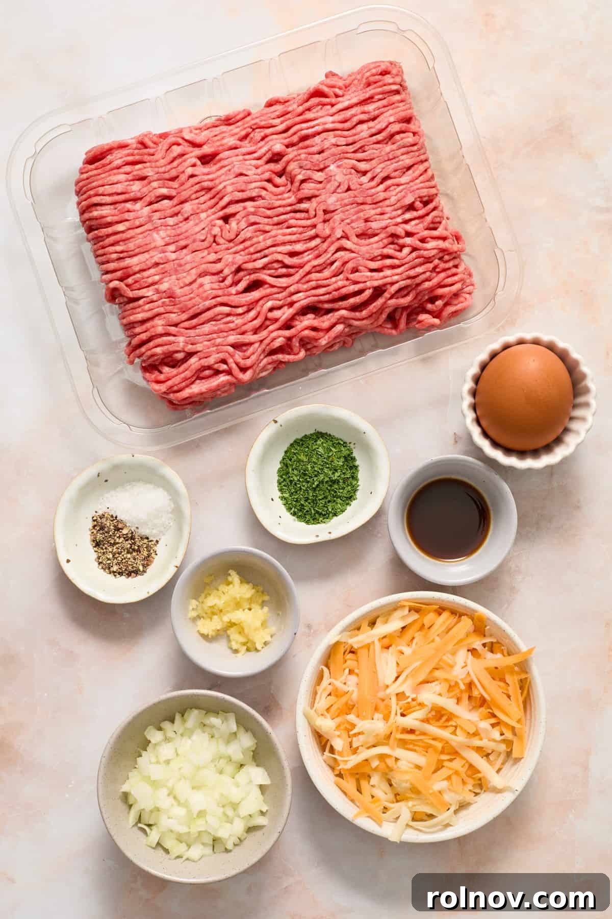 The Ultimate Air Fryer Burger 3 All the essential ingredients for air fryer hamburgers, including ground beef, diced onion, shredded cheese, egg, Worcestershire sauce, minced garlic, parsley, salt, and pepper, meticulously prepped and arranged for cooking.