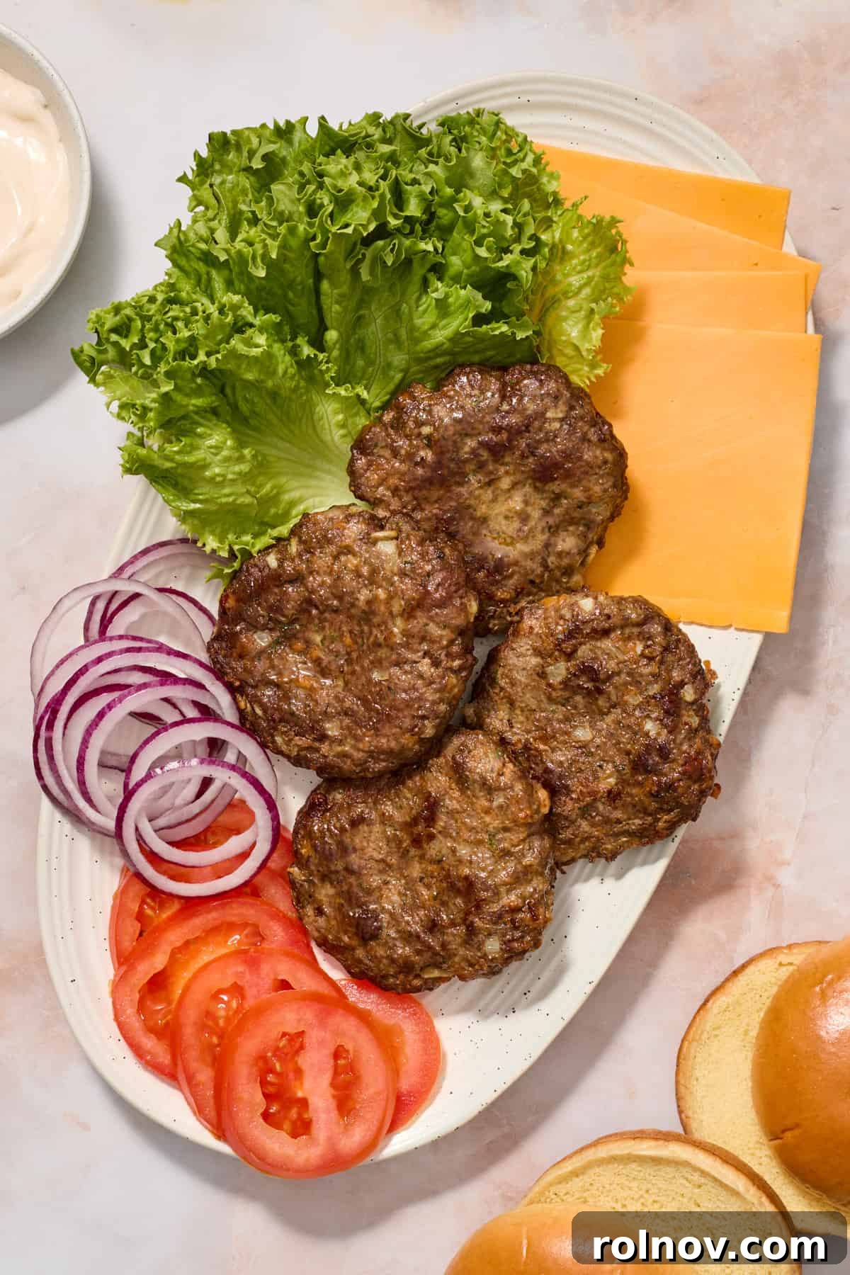 The Ultimate Air Fryer Burger 9 A vibrant platter featuring perfectly cooked hamburger patties, fresh lettuce, sliced tomatoes, red onion, and cheese slices, ready for serving and customization.