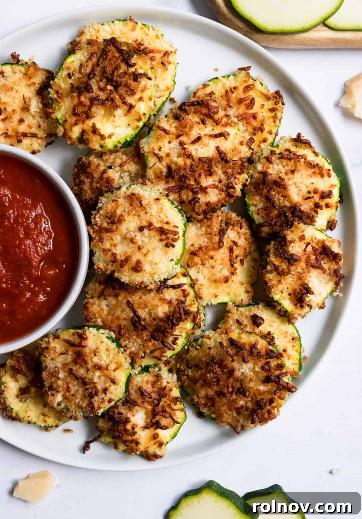 Crispy Three Cheese Air Fryer Zucchini 6 Overhead shot of a white plate filled with perfectly crispy, golden-brown air-fried zucchini rounds, ready to be enjoyed.