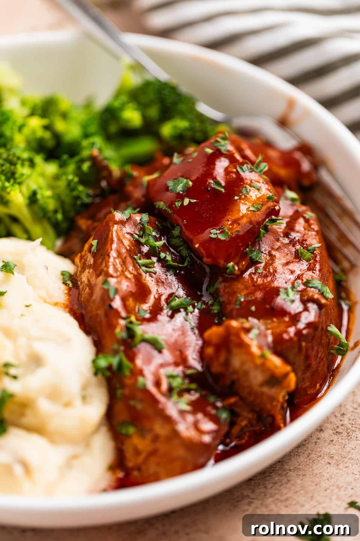 Slow Cooker BBQ Country Style Ribs 3 White plate showcasing BBQ sauce-covered boneless pork ribs, served alongside roasted potatoes and fresh broccoli.