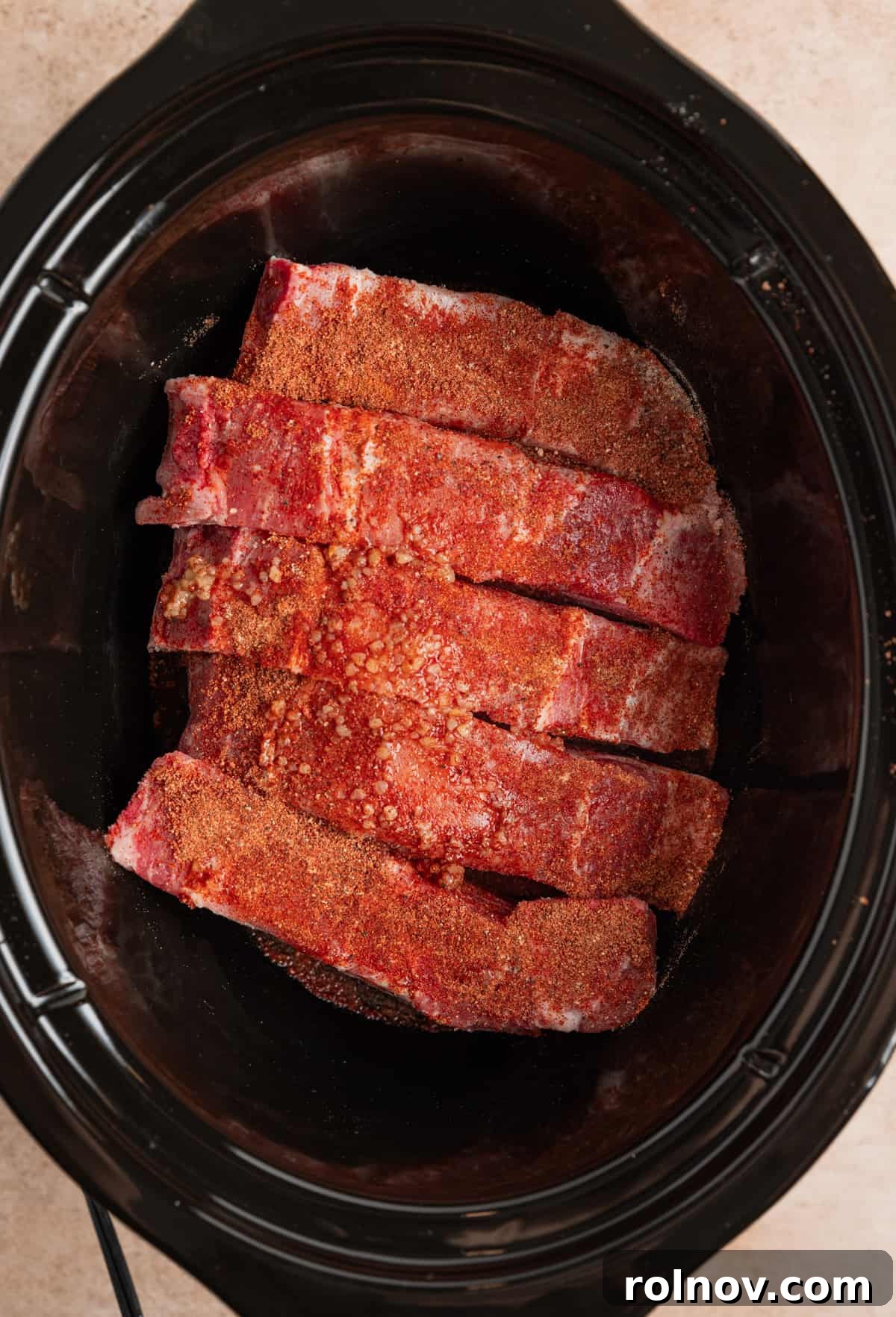 Slow Cooker BBQ Country Style Ribs 5 Country style boneless pork ribs neatly arranged in a slow cooker, seasoned with dry rub over top.